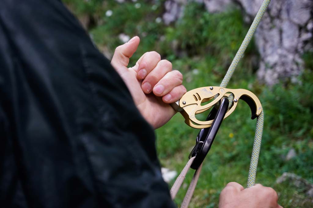 Das Bild zeigt einen goldenen Austrialpin Fish Autotuber beim Ablassen. Ein Kletterer hat beide Hände am Gerät.