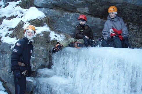 Kinder probieren sich beim Eisklettern in Tirol