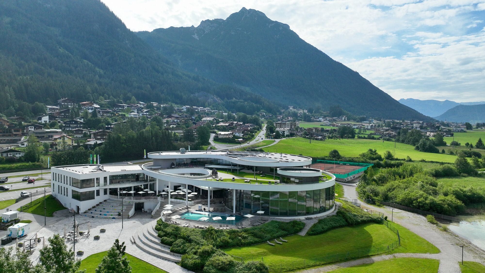 So schaut das Freizeitzentrum in Achensee aus der Entfernung aus. Der Wasserbereich ist von einer Glasfront umgeben. 