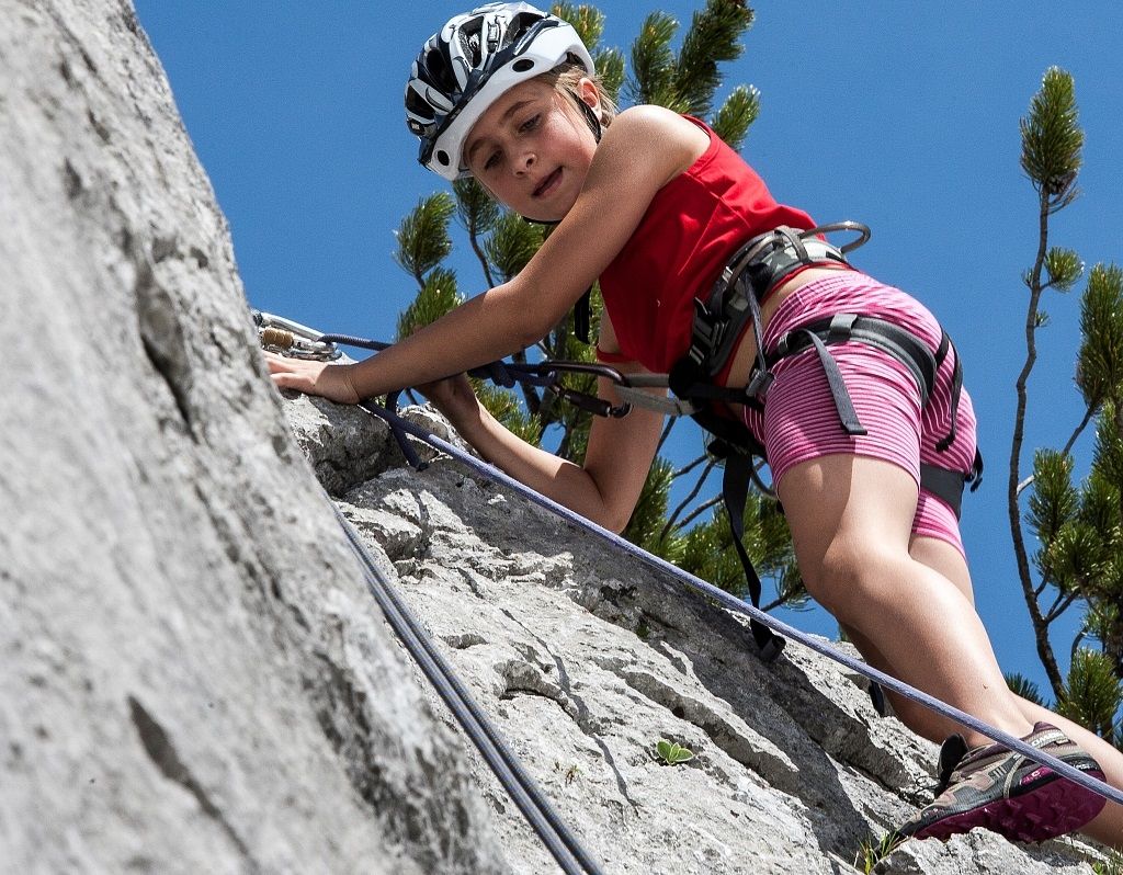 Kind klettert mit Helm an einer Kalkwand im Wilden Kaiser