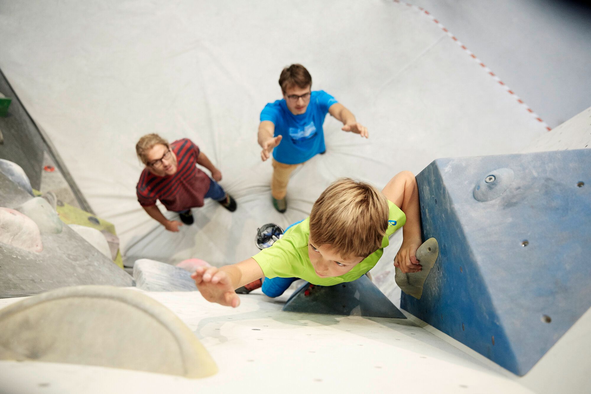 Ein Kind bouldert in der Bergstation in Telfs. Zwei Personen sichern das Kind.