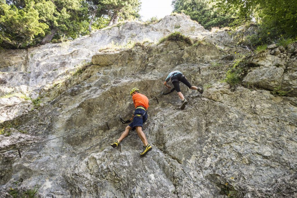 Person am Übungsklettersteig vor der Kulisse des Kaisergebirges