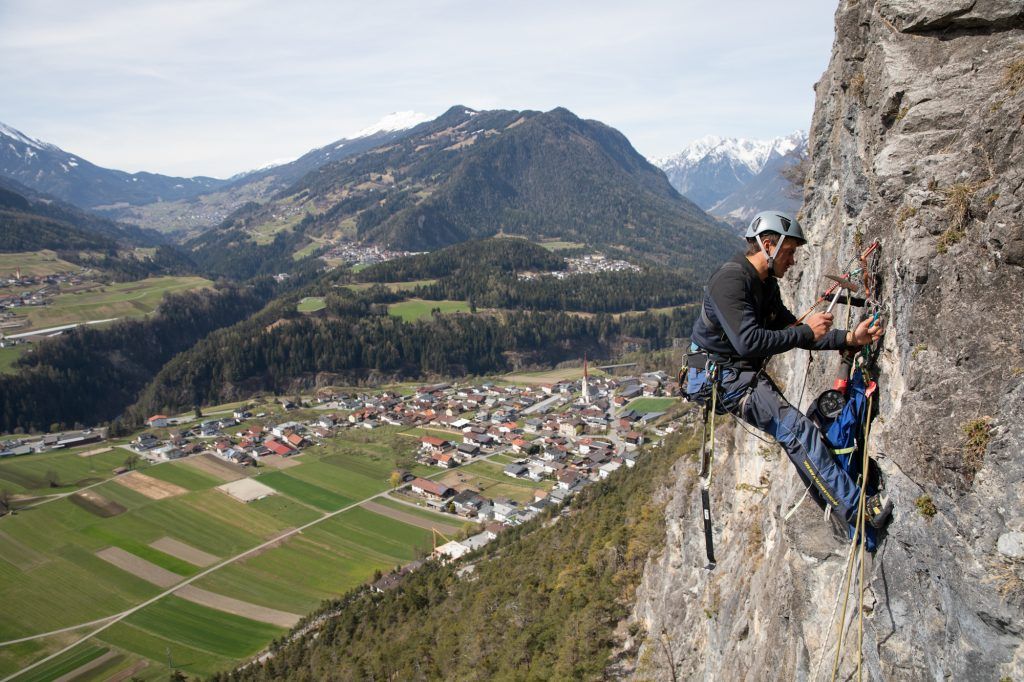 Das Bild zeigt einen Kletterer beim Bohren in einer Felswand.