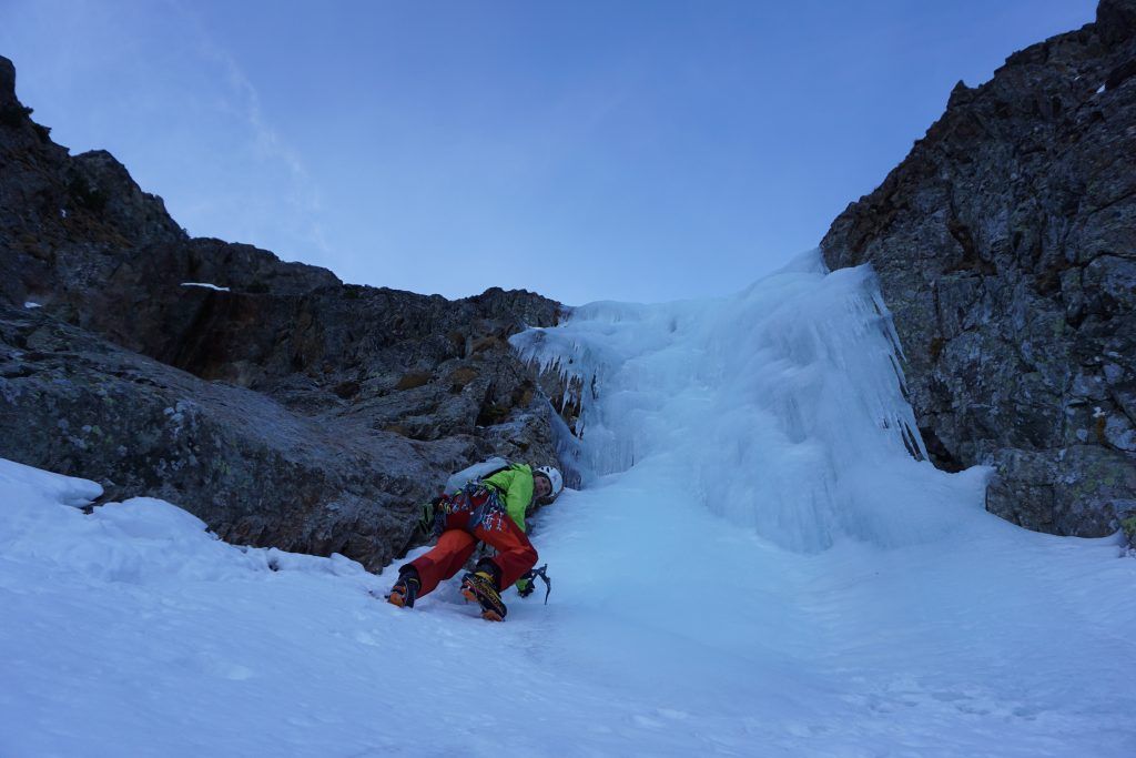 Alpinist in einem steilen, schmalen Eisaufschwung