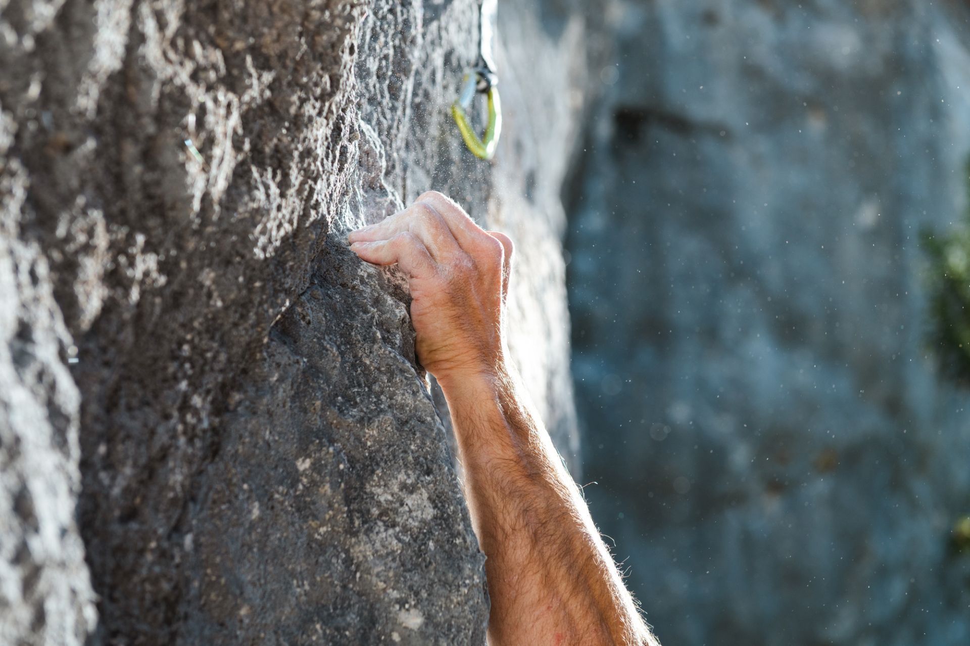 Die Hand eines Mannes hält sich an einem Felsen fest.