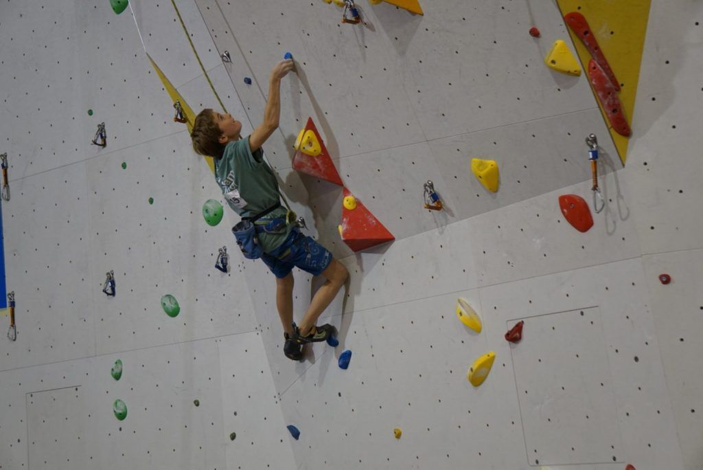 Kind klettert bei einem Wettkampf an einer Kletterwand
