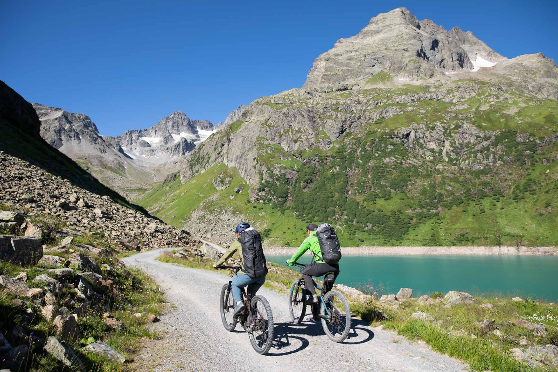 Zwei Fahrradfahrer fahren an einem Teich entlang.