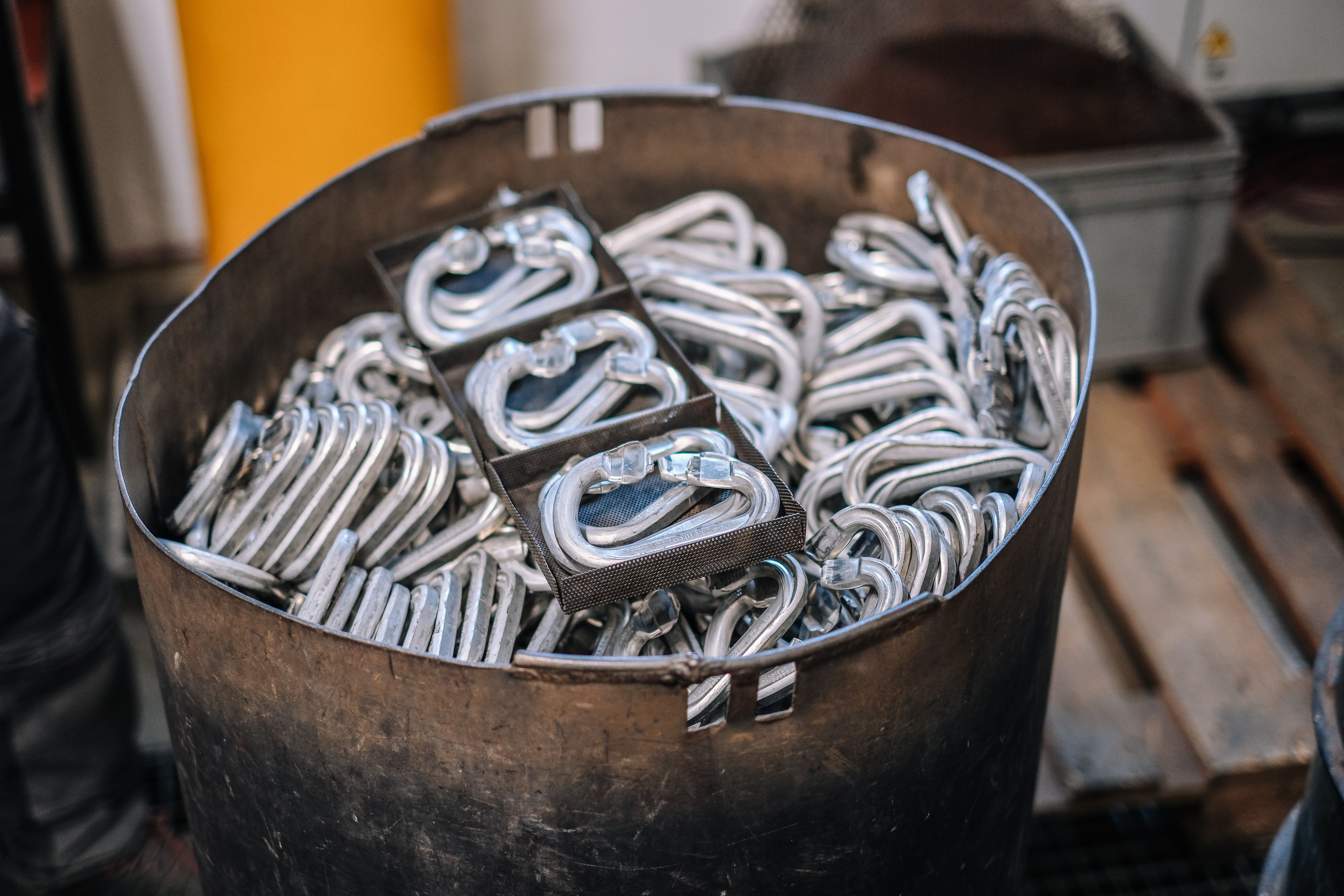 Metallbehälter voller geschmiedeter Karabiner-Rohlinge mit Schmiedegrat