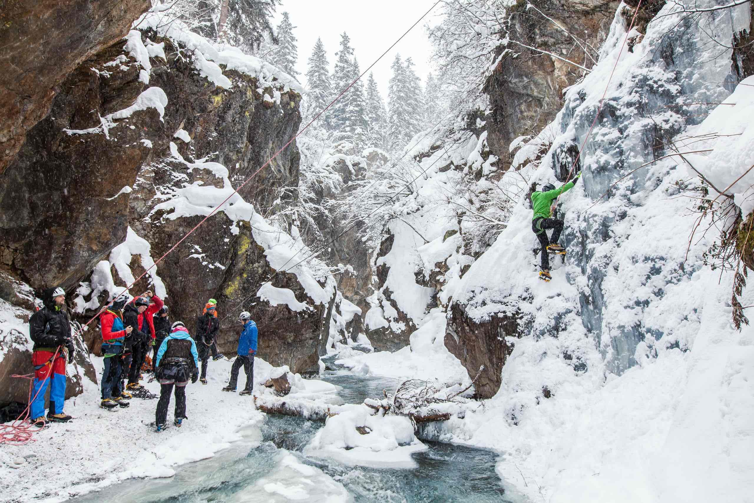 Eiskletterer in einem gefrorenen Wasserfall im winterlichen Gelände