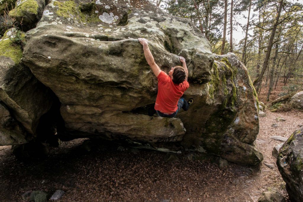 Boulderer an einem Felsblock im Wald