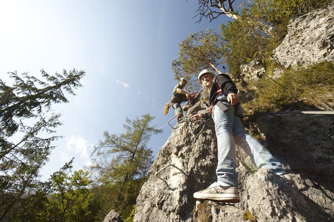 Kletterer am Klettersteig St. Adolari zwischen Bäumen