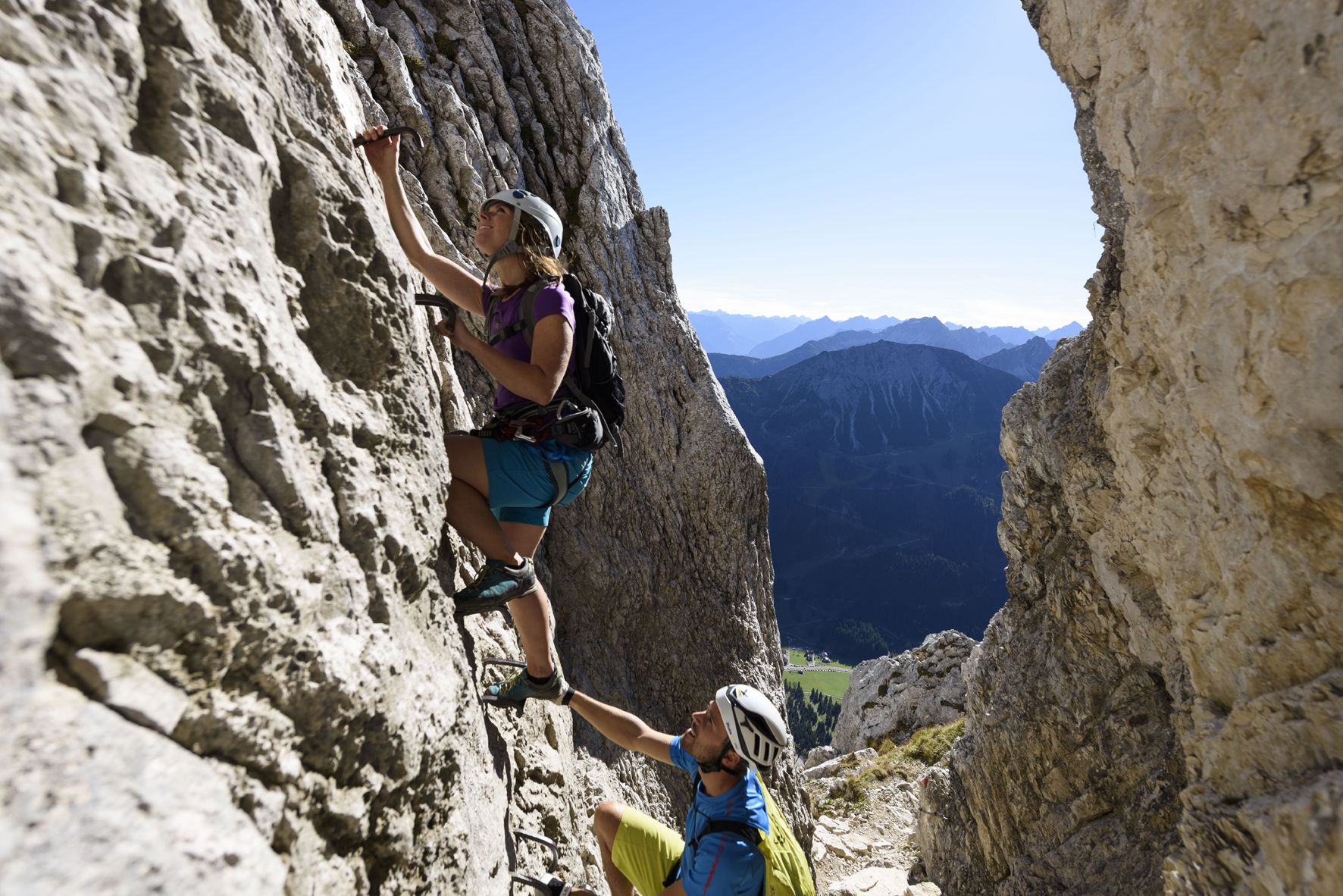 A via ferrata climber on the wire rope with a view over the Tannheimer Valley