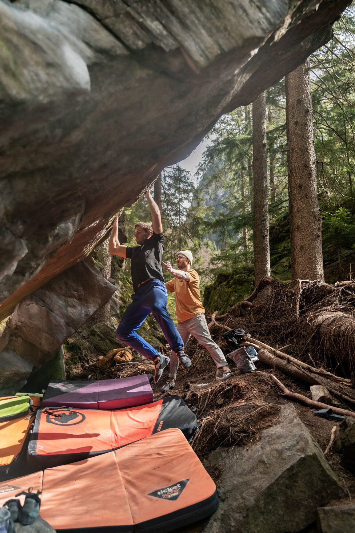 Boulderer mit Matten und Spotter am Fels