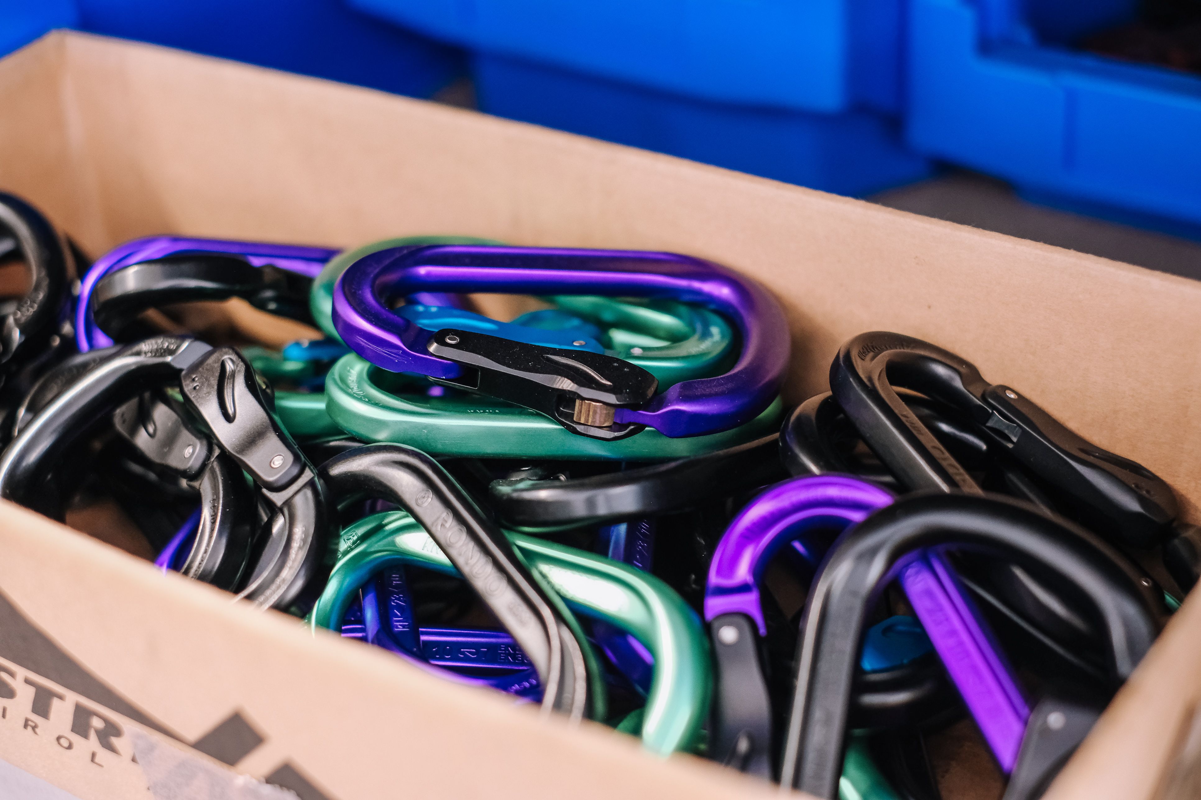 Karton voller eloxierter Karabiner in Violett, Grün, Schwarz und Grau