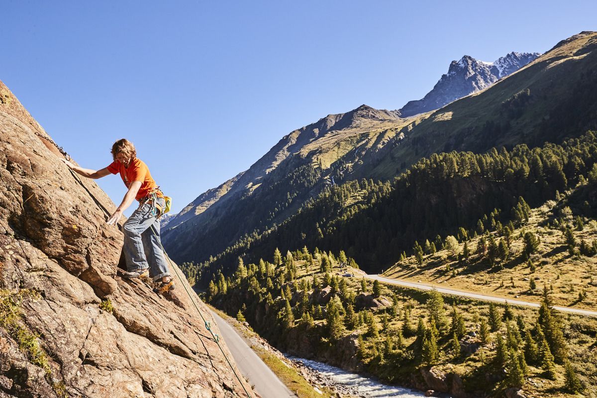 Kletterin an einer schattigen Felswand an einem heißen Sommertag