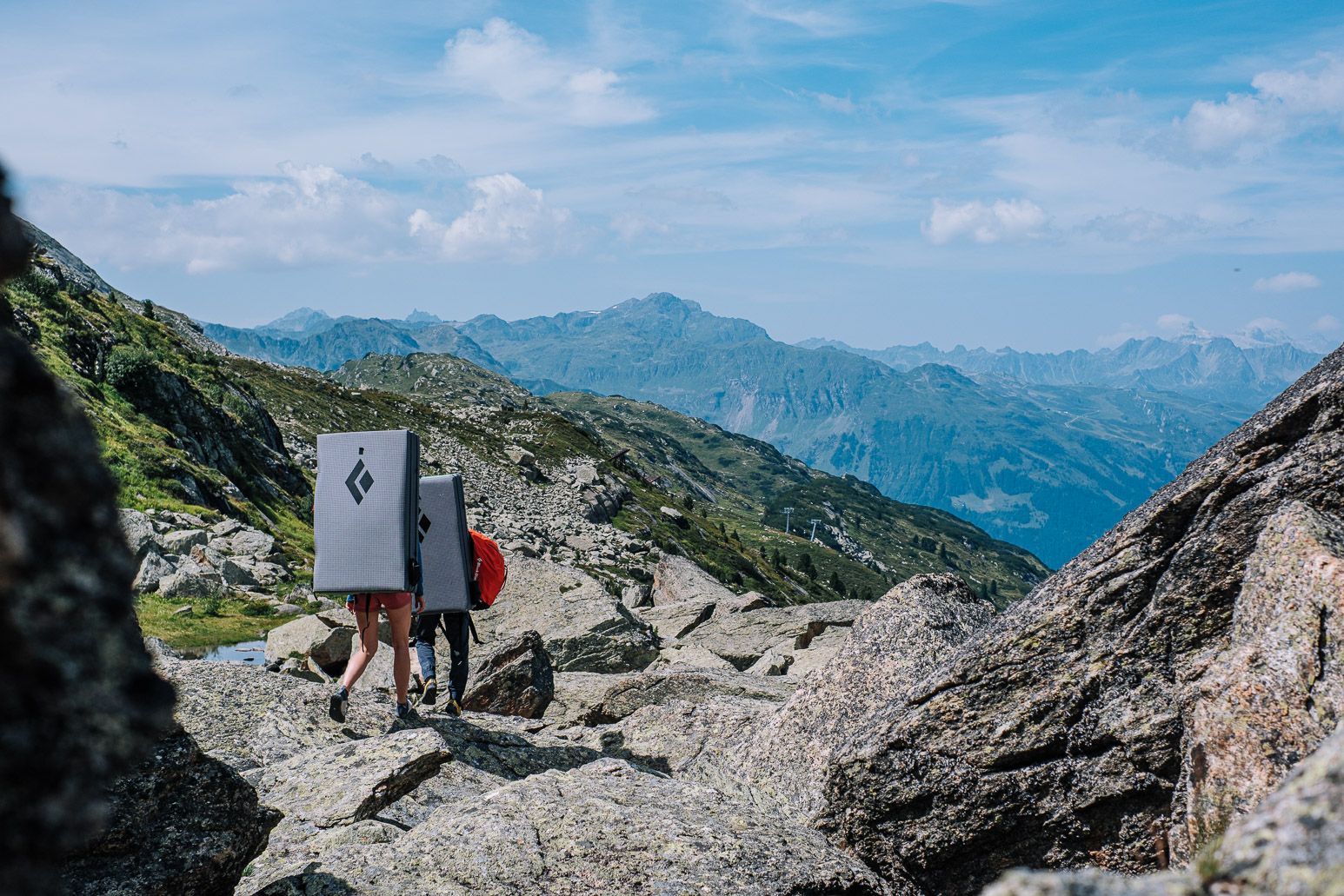 Zwei Personen gehen mit Ausrüstung auf einem Berg.