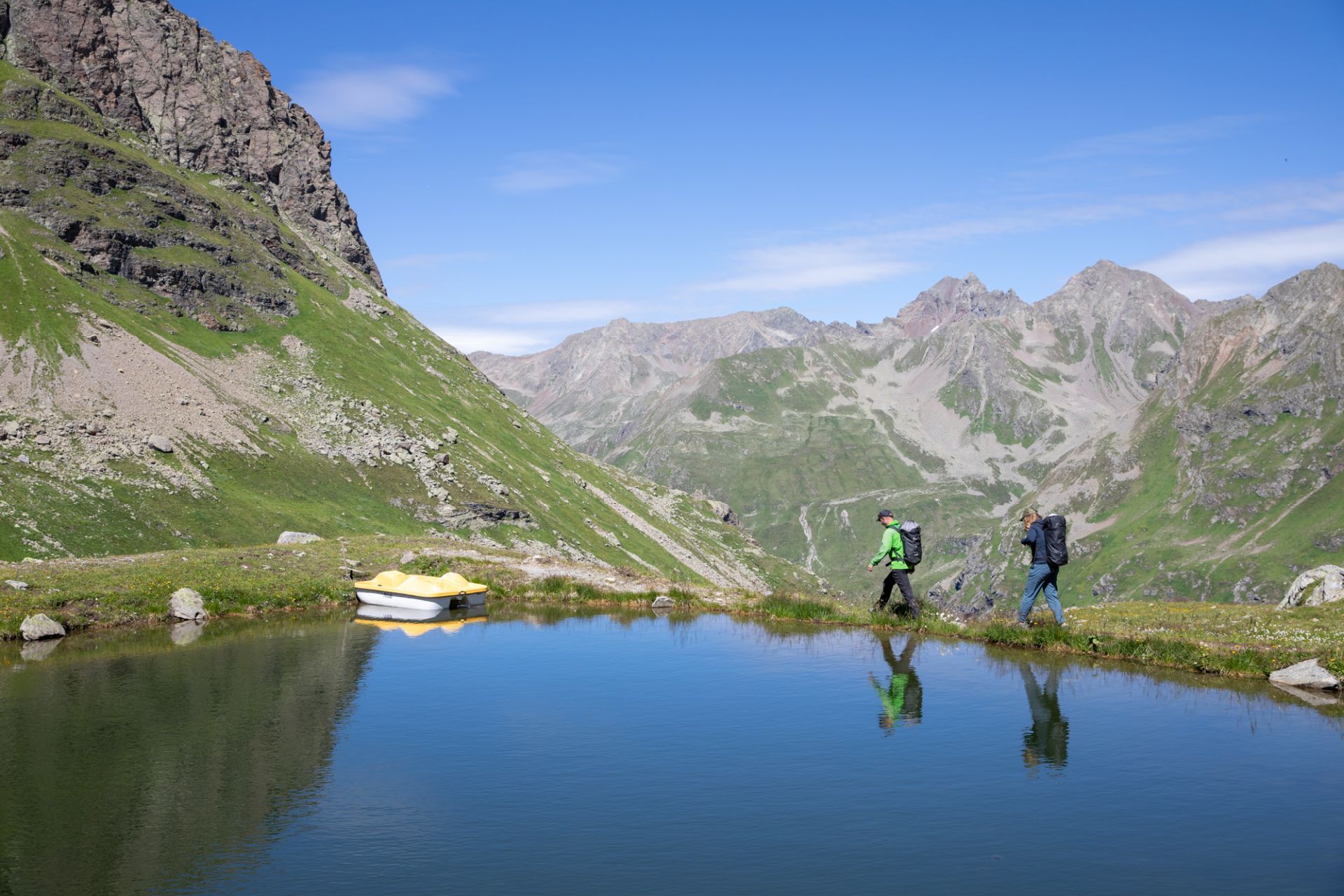 Zwei Personen gehen an einem See entlang.