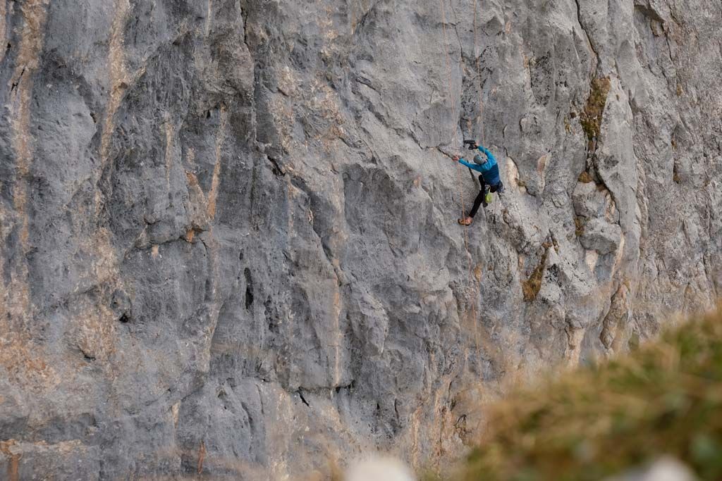 Kletterer bohrt einen Bohrhaken in der ersten Seillänge