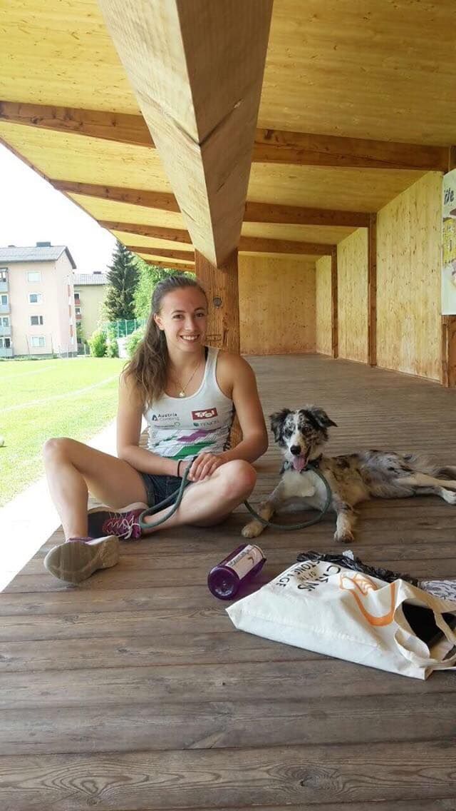 Julia Fiser sitzt mit ihrem Hund auf einem Holzboden