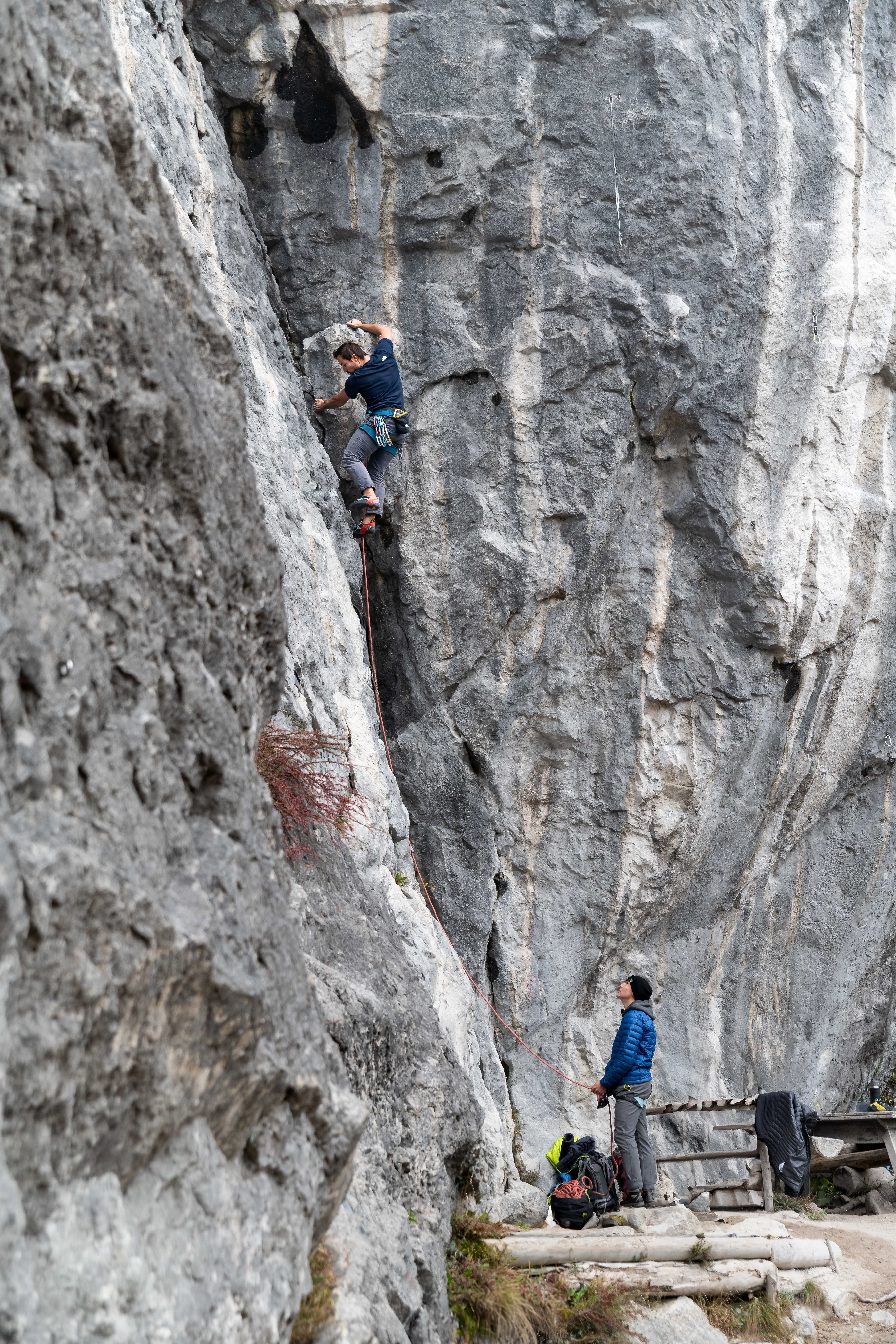 Climber on a vertical route in Morsbach with belayers at the foot of the wall, portrait format