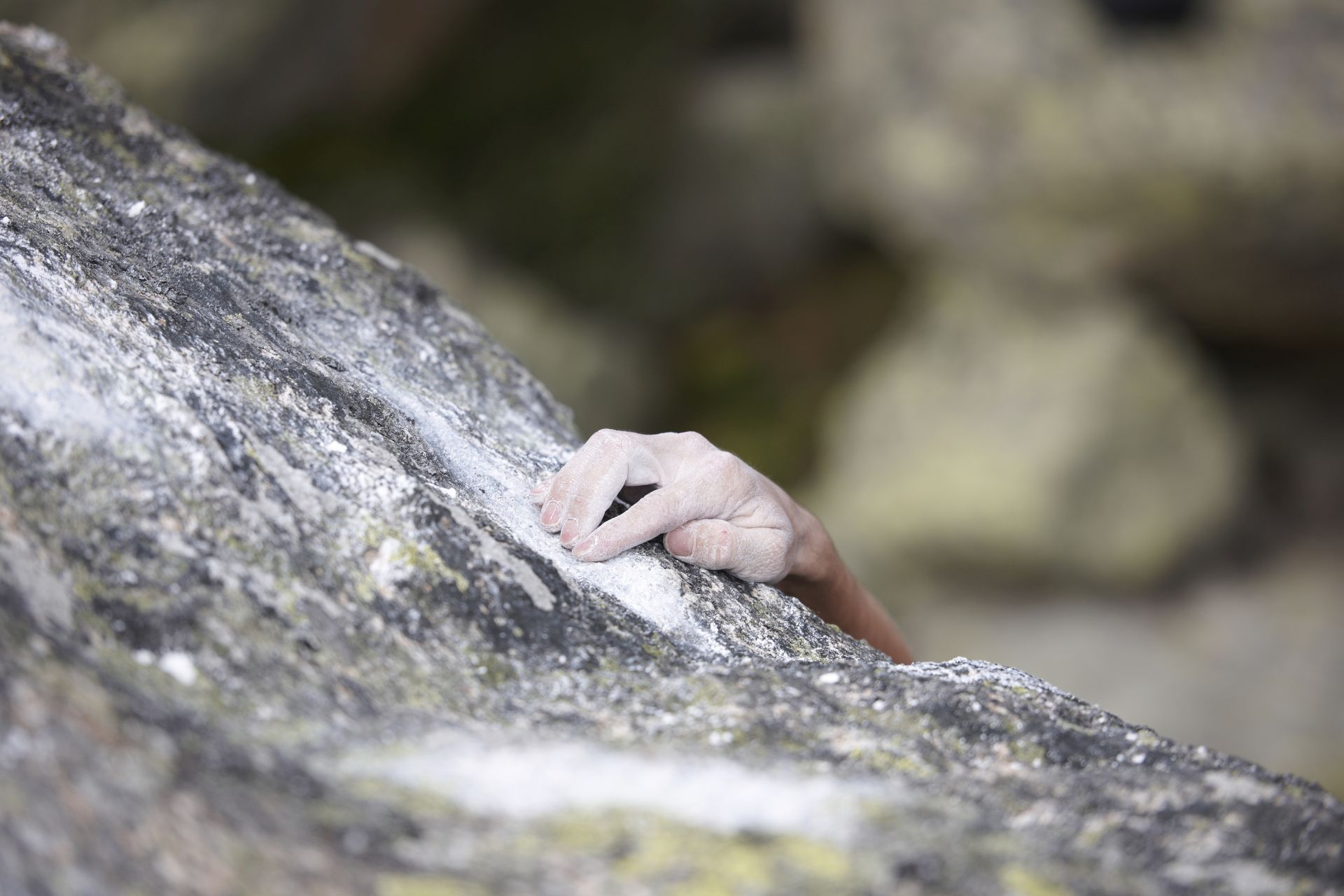 Eine Hand hält sich an einem Felsen fest.