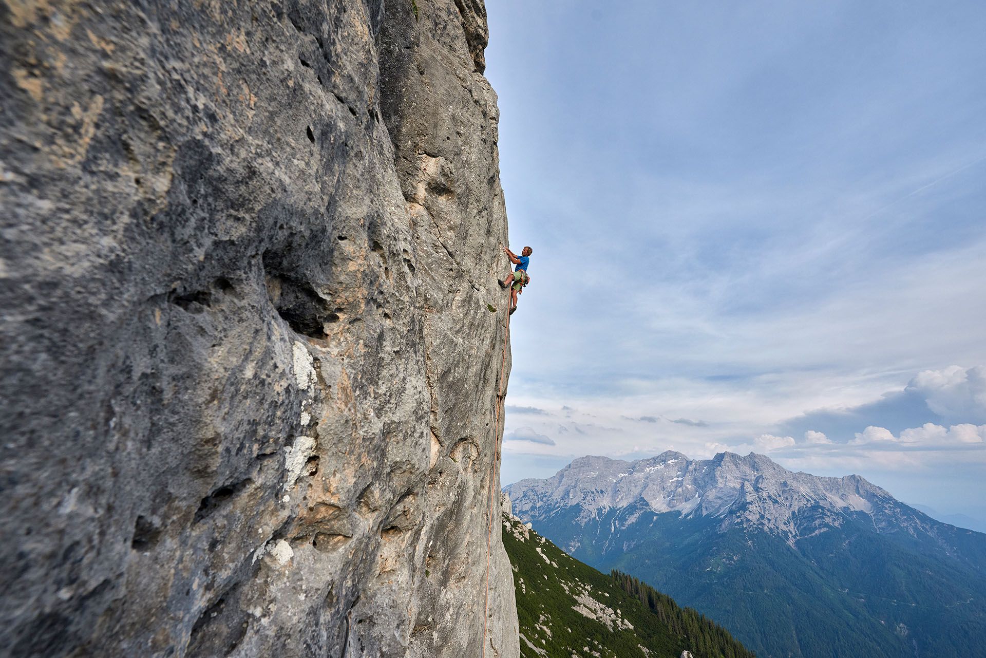 Kletterer in einer alpinen Felswand mit Blick auf die Berge
