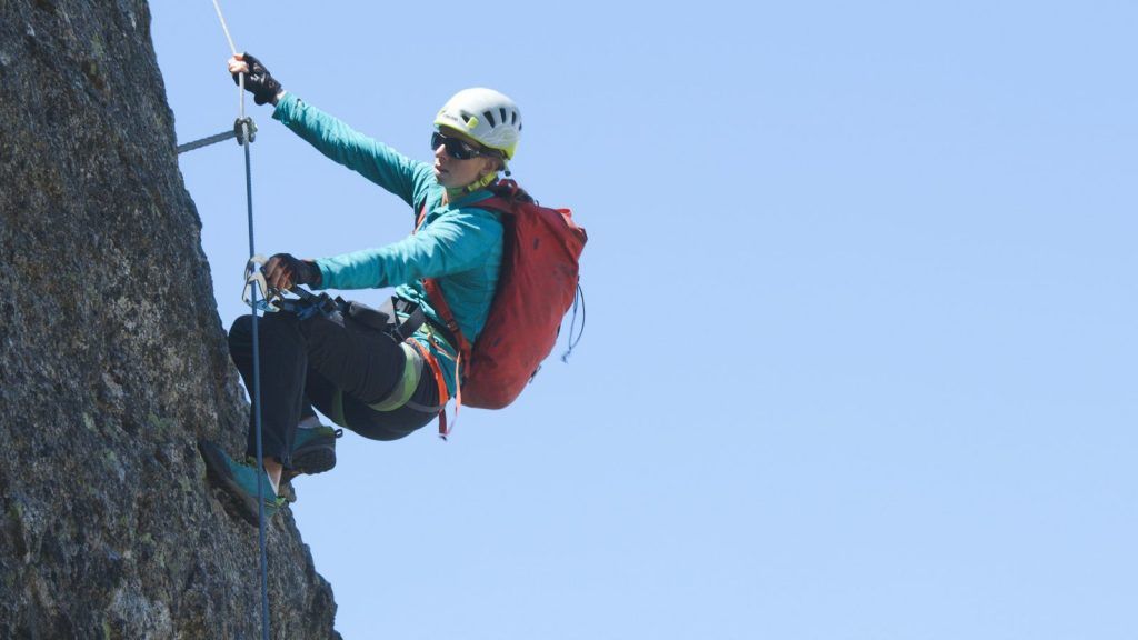 Hand clips a via ferrata carabiner onto an anchor point